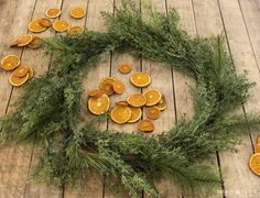 an arrangement of dried oranges arranged in a circle on a wooden floor with greenery