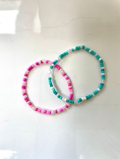 two bracelets sitting on top of a white table next to each other with beads