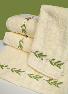 three towels with green leaves on them sitting on a table