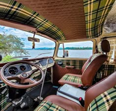 the interior of an old car with plaid upholstered seats and steering wheel covers