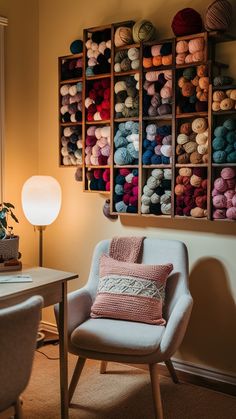 a chair and lamp in front of a wall filled with balls of yarn on it