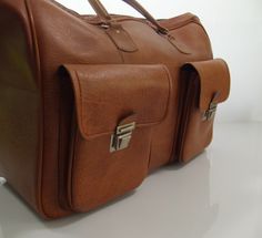 Vintage brown imitation leather sportsbag / weekend bag from the 70s In good condition 2 front pockets Sizes H xW x D ± 35 x 51 x 21 cm Brown Duffle Bag With Pockets, Everyday Brown Duffle Bag With Pockets, Brown Tote Bag With Multiple Pockets, Brown Duffle Bag With Pockets For Daily Use, Vintage Duffle Bag With Luggage Sleeve For Trips, Vintage Satchel Duffle Bag For Trips, Retro Cognac Shoulder Bag For Travel, Brown Travel Weekender Bag With Pockets, Brown Weekender Bag With Pockets For Travel