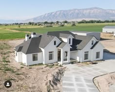 an aerial view of a house in the middle of a field with mountains in the background