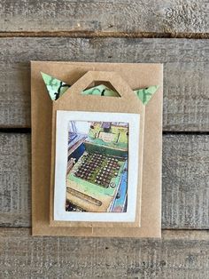 an old fashioned typewriter in a brown card with green ribbon hanging from it's side