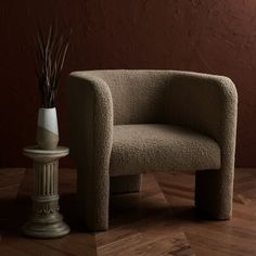 a small chair next to a white vase on a wooden floor