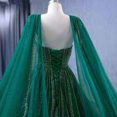 a green dress with sequins on it and a cape around the neckline