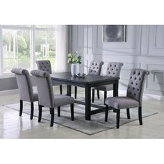 a dining room table with grey chairs and a rug on the floor in front of it