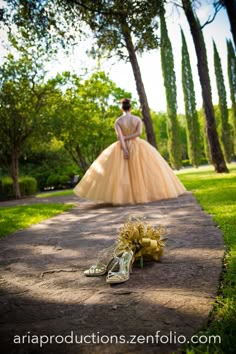 a woman in a ball gown standing next to a pair of shoes