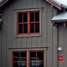 a gray house with red windows and a metal roof