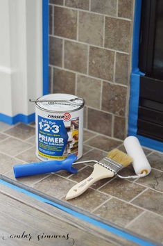 a paint can and brush sitting on the ground next to a tile floor in front of a fireplace