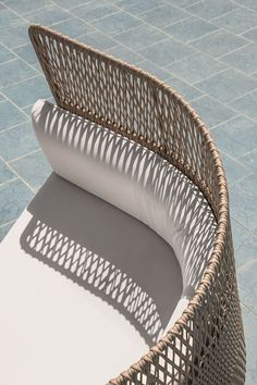 a wicker chair sitting on top of a blue tile floor next to a white pillow