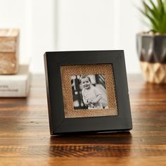 a black frame with a photo on it sitting on a table next to some books and a potted plant