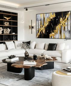 a living room with white couches and black tables in front of a large painting