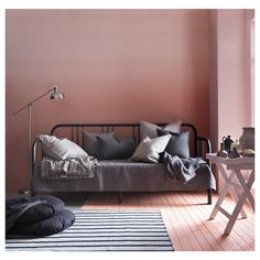 a living room with pink walls and black metal bed in the middle, white rug on the floor