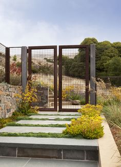 a garden with stone steps leading up to a gate