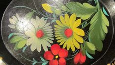 a black plate with yellow and red flowers painted on it