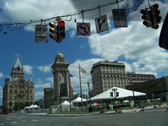 an intersection with traffic lights and buildings in the background on a partly cloudy day,