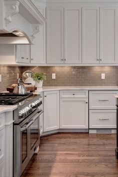 a kitchen with white cabinets and wood floors