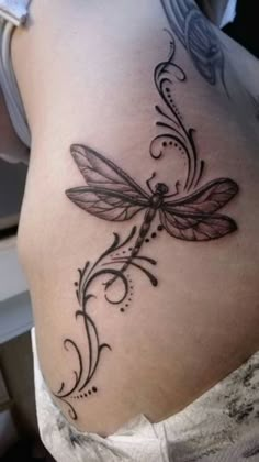 a woman's stomach with a dragonfly tattoo on the side and an intricate design