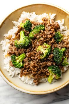 a bowl filled with rice, meat and broccoli on top of a table