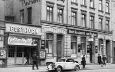 an old black and white photo of people walking on the sidewalk in front of a post office