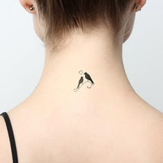 the back of a woman's neck with a small bird tattoo on her left side