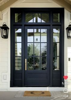 a black front door with two lanterns on the side