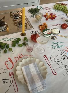 a table topped with plates and glasses filled with food on top of a white table cloth