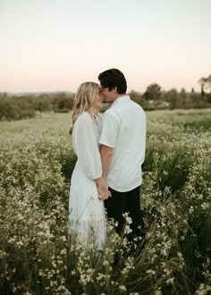 a man and woman are standing in the middle of a field with wildflowers