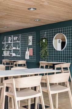 an empty restaurant with tables and chairs in front of a green wall that has pictures on it