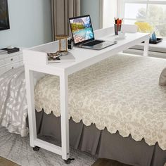 a laptop computer sitting on top of a white desk next to a bed in a bedroom