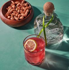 a bottle of gin next to a glass filled with almonds