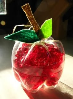 an apple shaped container filled with candy sitting on top of a table