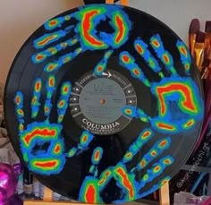 a record covered in colorful images on a wooden stand next to other records and art supplies