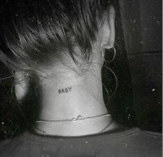 a woman's neck with the word baby tattooed on her left side ribcage