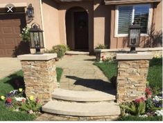 a house with stone steps leading to the front door and entry way that leads up to the driveway