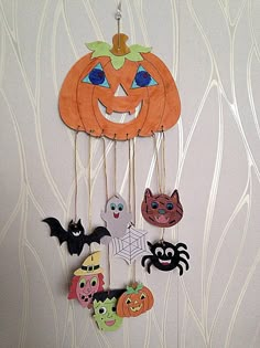 a paper plate with halloween decorations hanging from it's sides on a white wall