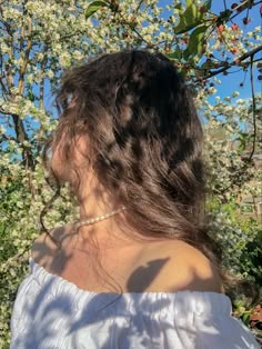 a woman standing in front of a tree with white flowers on it's branches