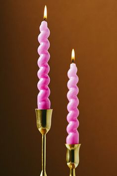 two pink candles are sitting on top of each other with one candle in the middle