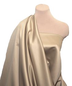 a mannequin wearing a beige dress with a draped over it's shoulder