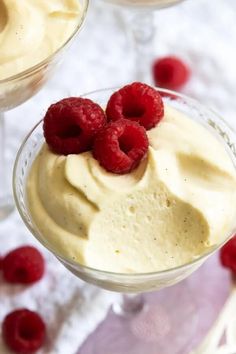 two desserts with raspberries on top in glasses