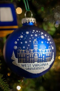 a blue ornament hanging from a christmas tree in front of a lit up building