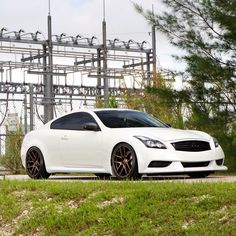 a white sports car parked in front of an electrical substation with power lines behind it