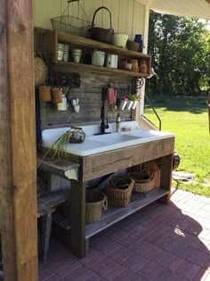 a sink sitting under a wooden structure on top of a brick floor next to a green field