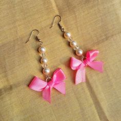 two pink bows and pearls are hanging from earrings