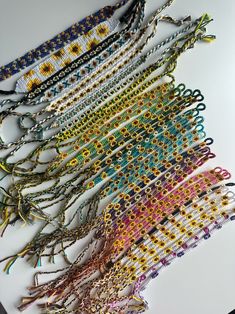 several rows of bracelets are laid out on a table top with beads and chains hanging from them