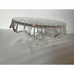 a clear glass cake plate sitting on top of a white tablecloth covered flooring