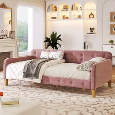 a living room with a pink couch and white rug in front of a fire place