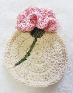 a crocheted flower sits on top of a white knitted pot holder with pink flowers