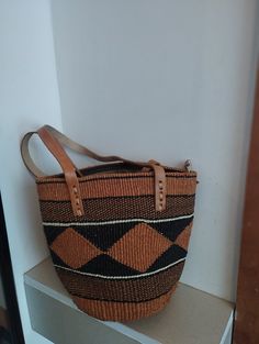 Geometrical earth tone sisal tote bag. Unique and stylish colorful sisal kiondo bag with stitched leather straps, pocket lining and zipper. Patterns and sizes slightly vary because weaving and stiching is done by hand. Ideal as a beach bag, shopping basket, market basket or storage basket. This unique tote bag is handmade by a group of ladies in a remote rural village in Machakos, Kenya. Do not clean with brush or water. If the bag gets wet, please dry to avoid dampness.  Leather type used is bo Handwoven Satchel Shoulder Bag For Daily Use, Handwoven Shoulder Satchel For Daily Use, Everyday Brown Woven Bucket Bag, Handheld Woven Satchel For Shopping, Everyday Brown Woven Bag, Brown Box Bag With Handles For Shopping, Brown Bucket Satchel With Top Carry Handle, Brown Crochet Bag With Handles For Shopping, Brown Bucket Satchel With Handles